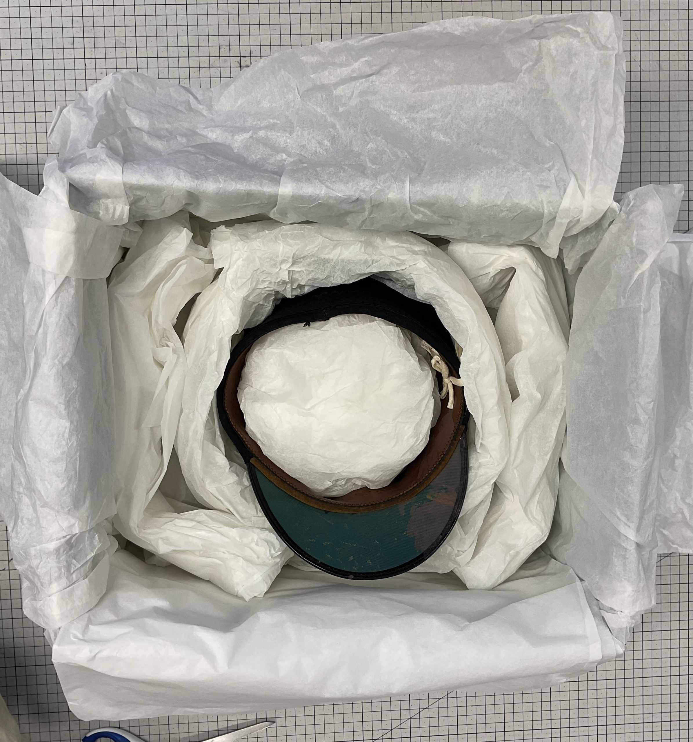 A hat inside a box, all wrapped with tisue