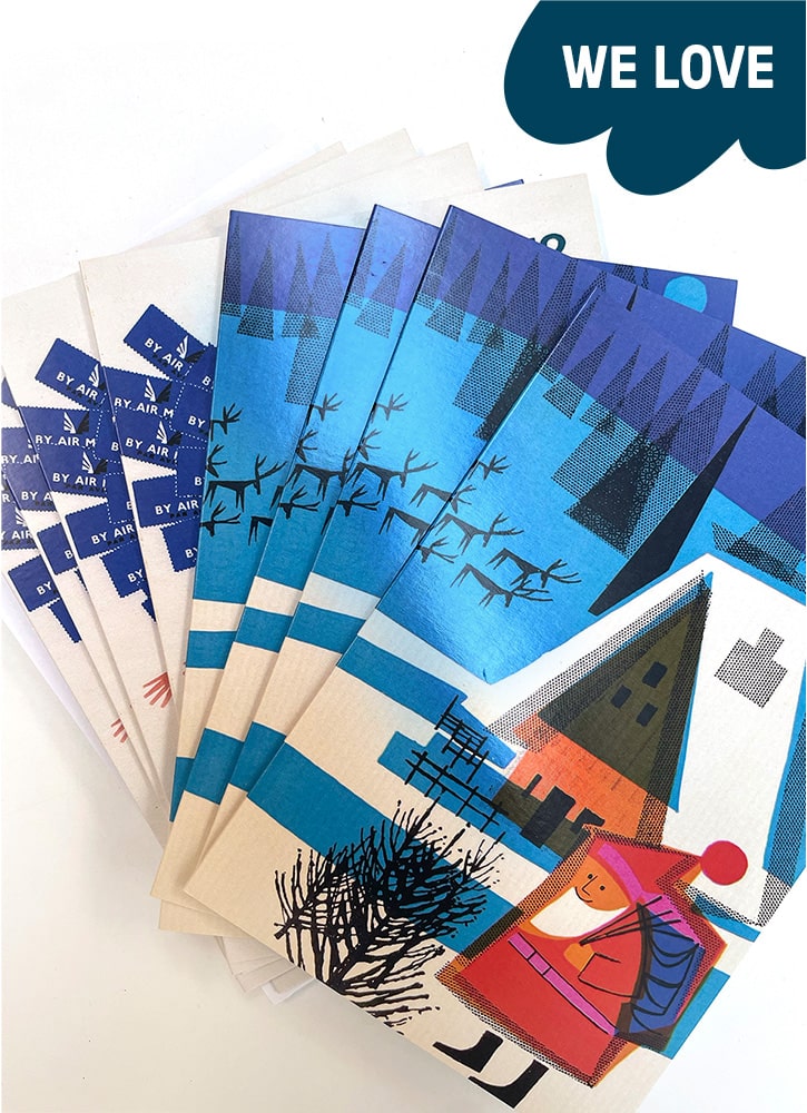 A selection of blue and white Christmas cards are spread out on a table