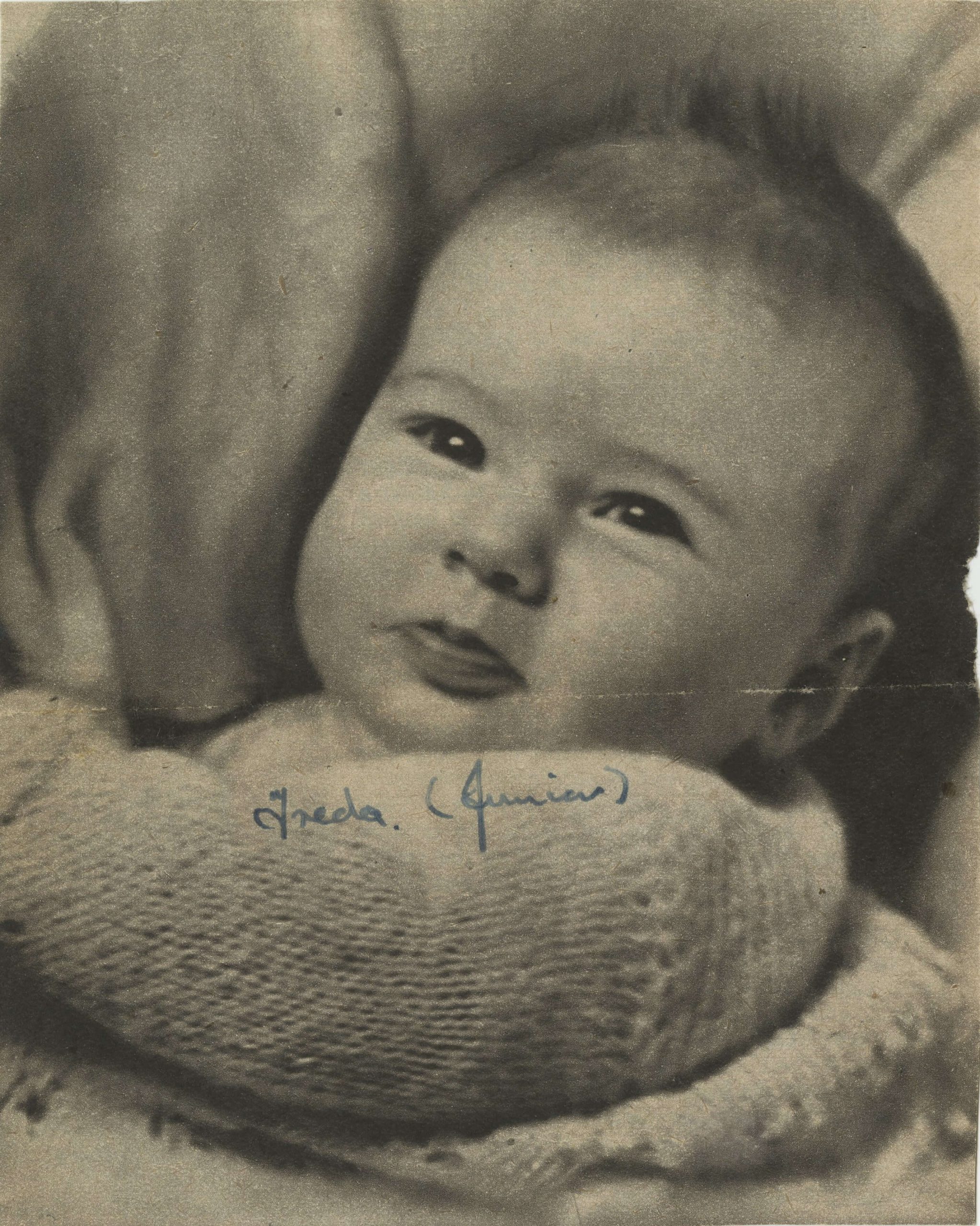 A black and white photo of a baby with the wording Freya (Junior) handwritten on it