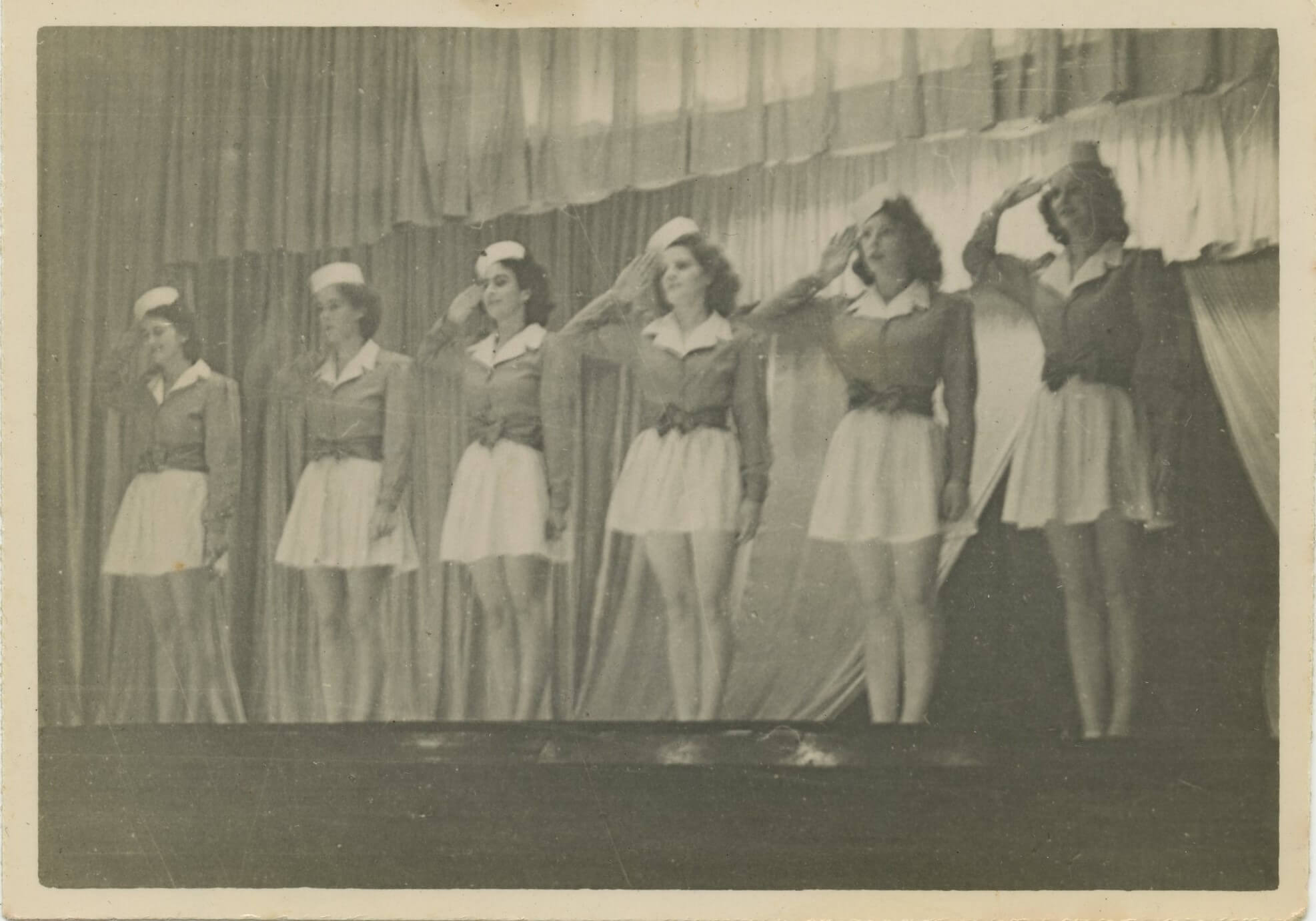A group of women wearing navy uniforms stay in line and salute