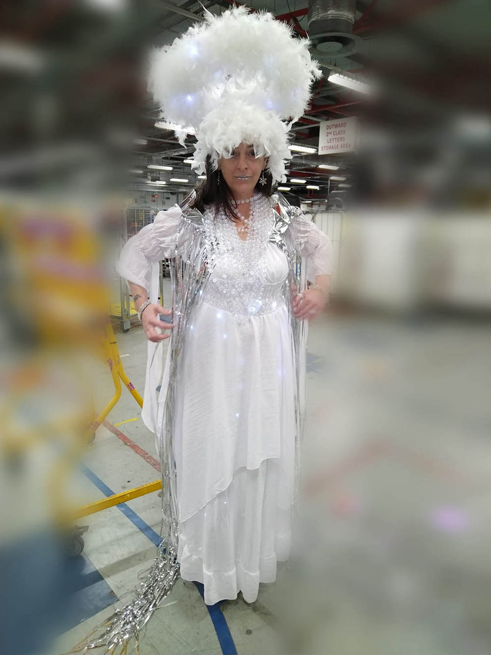 A woman in costume, wearing a white dress and feathered headdress.