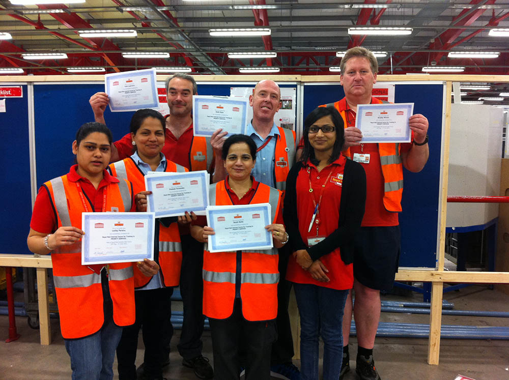 A group of postal workers in uniform, holding up certificates.