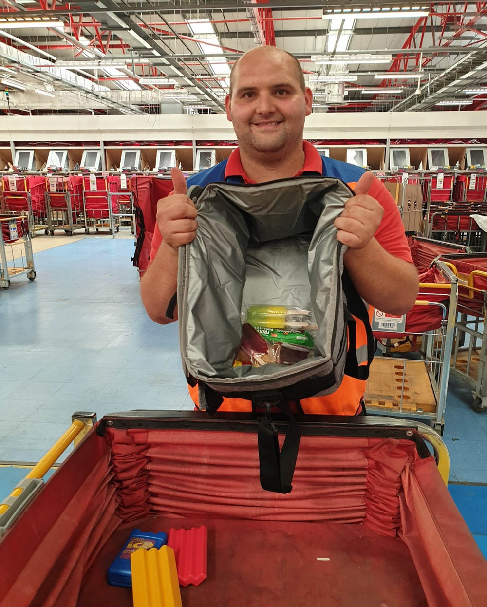 A postal worker holding up a bag of snacks at the mail centre.