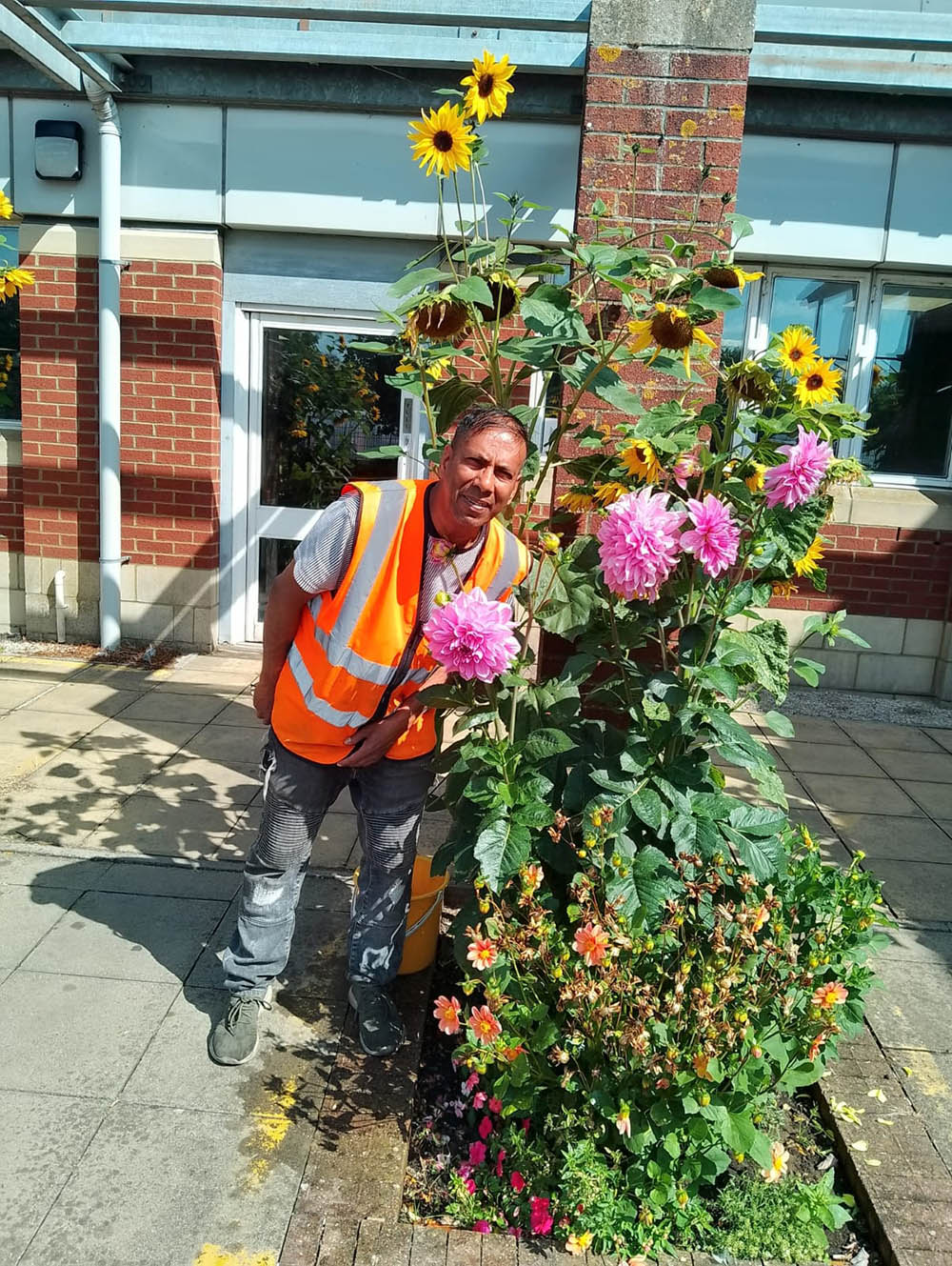Caetano standing next to flowers in the patio garden at the Swindon mail centre.