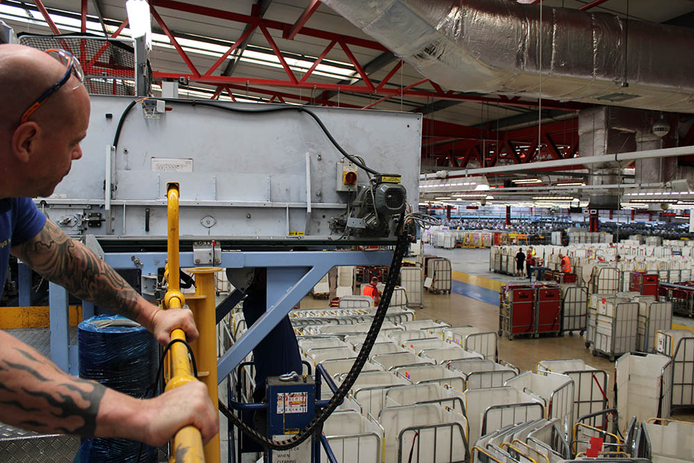 A postal worker with moving equipment at a sorting office.