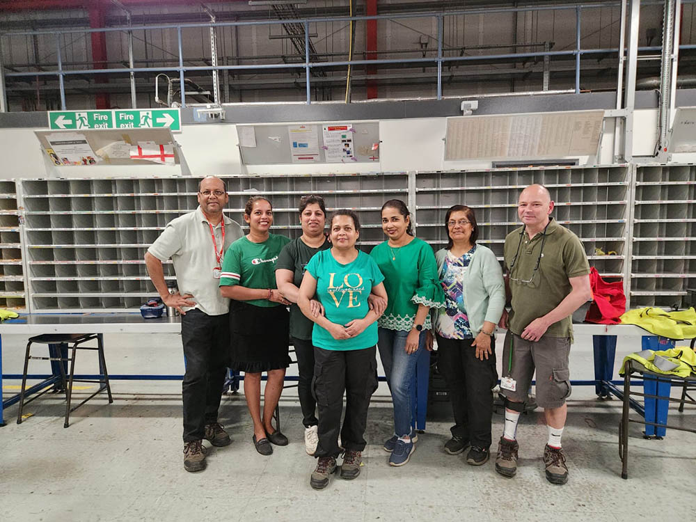A group of workers posing next to sorting equipment.