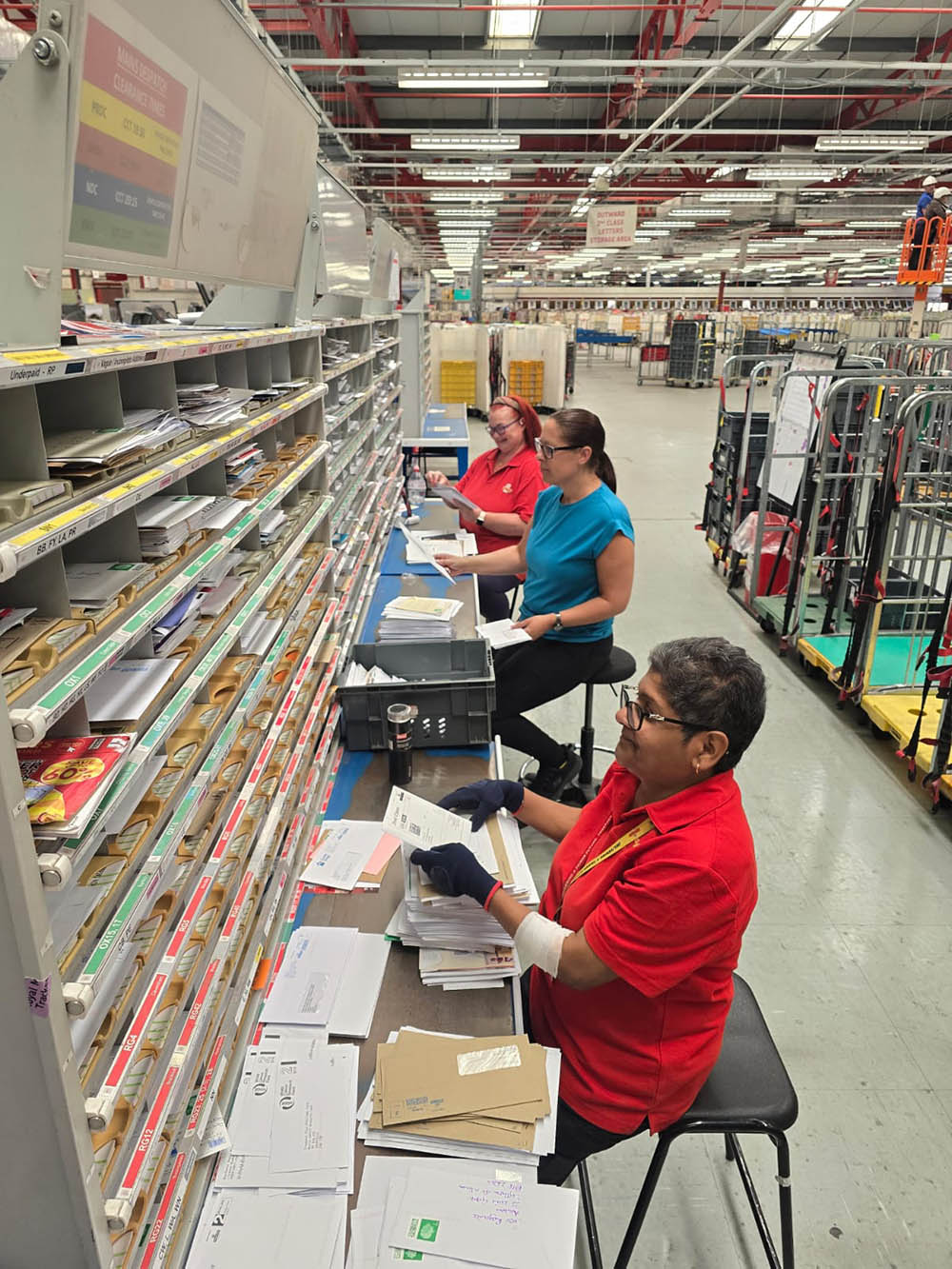 Postal workers working with sorting equipment.