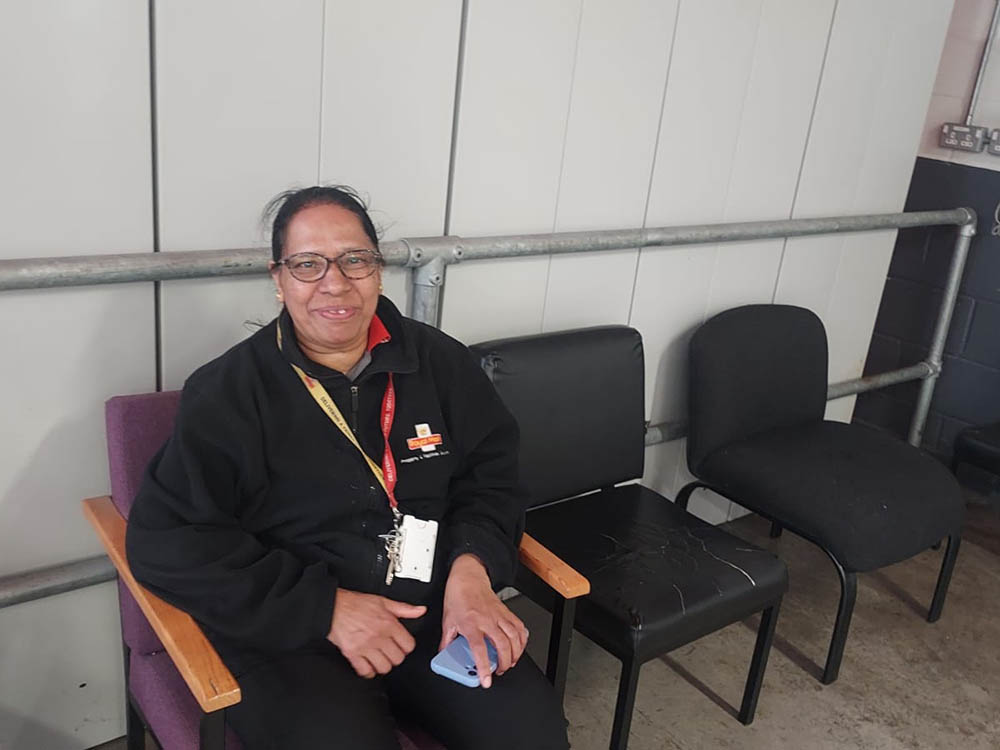 A woman in postal uniform seated in an office at the mail centre.