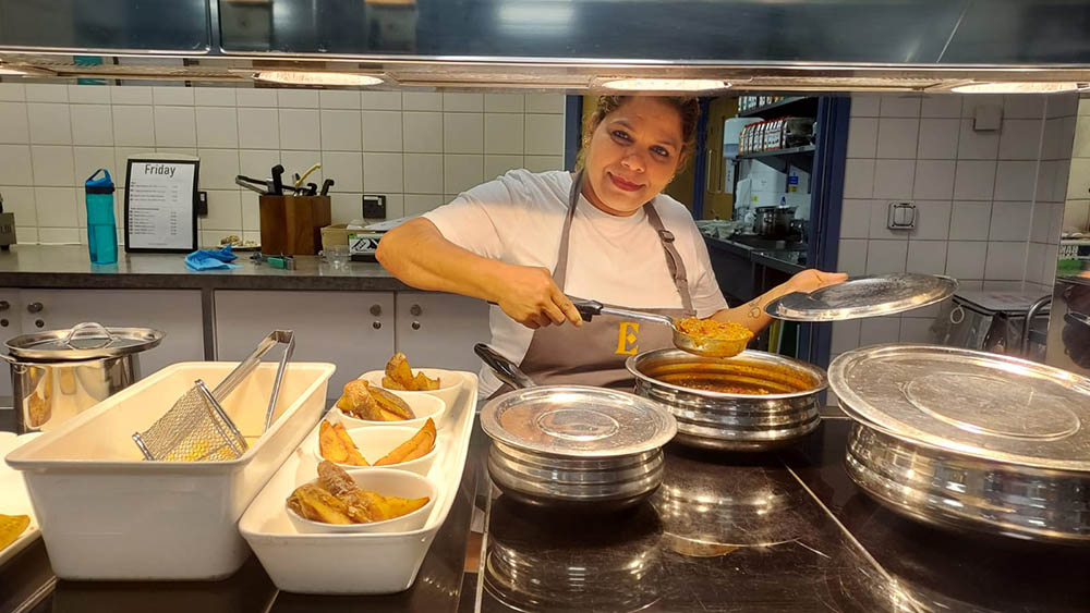 A canteen worker at the counter, serving food.
