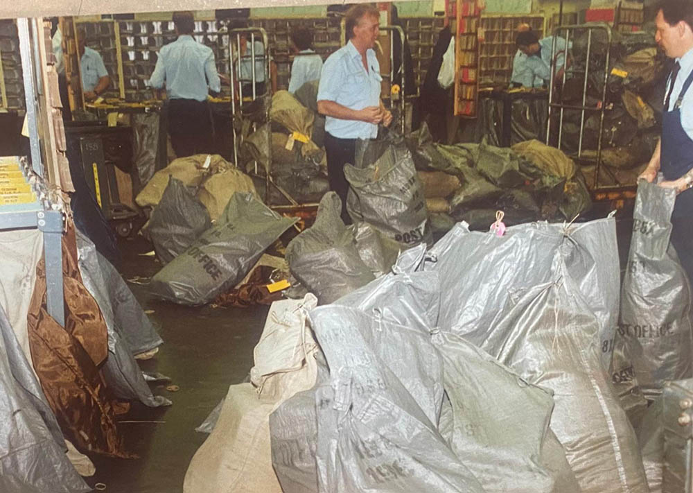 Postal workers sorting bags at a mail centre.