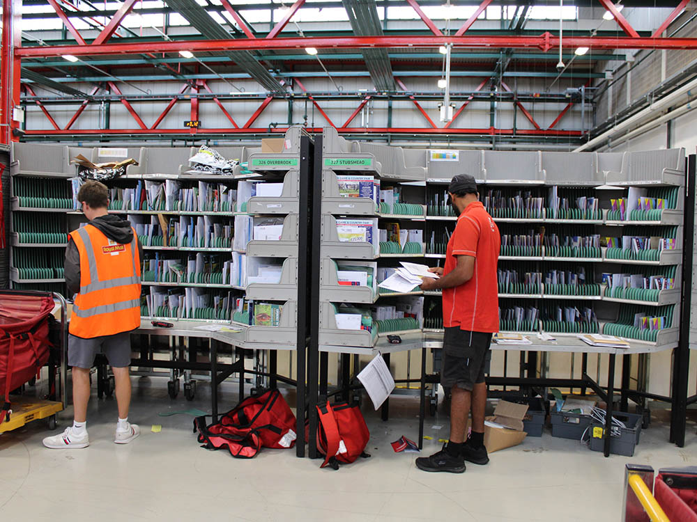 Uniformed postal workers with sorting equipment at the delivery office.