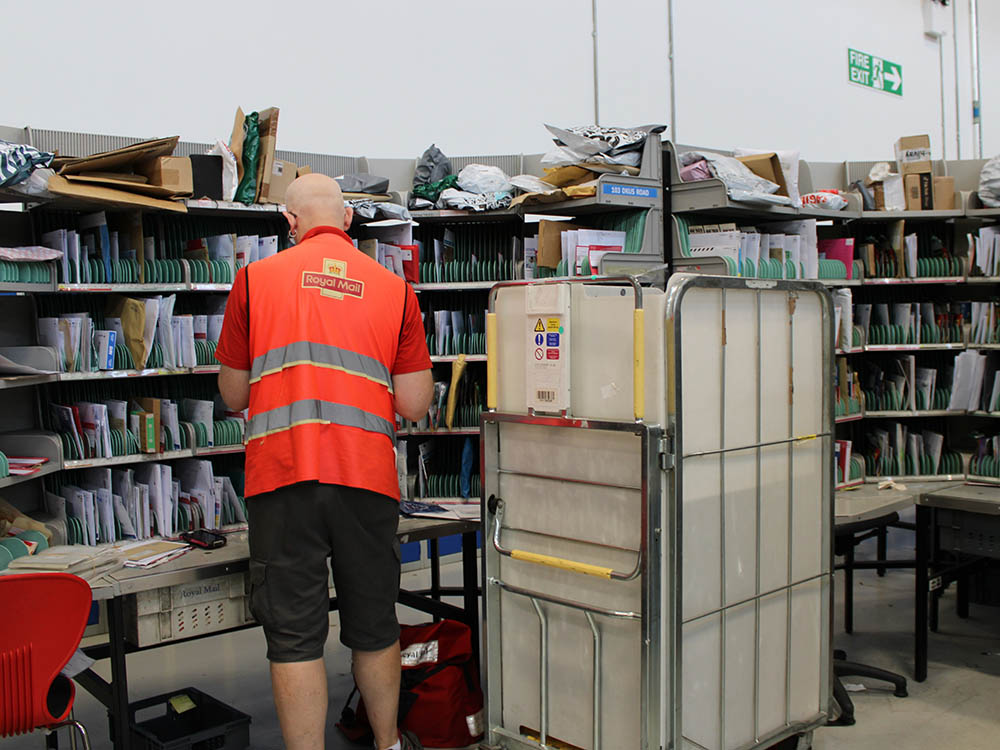 Uniformed postal workers with trolleys at the delivery office.