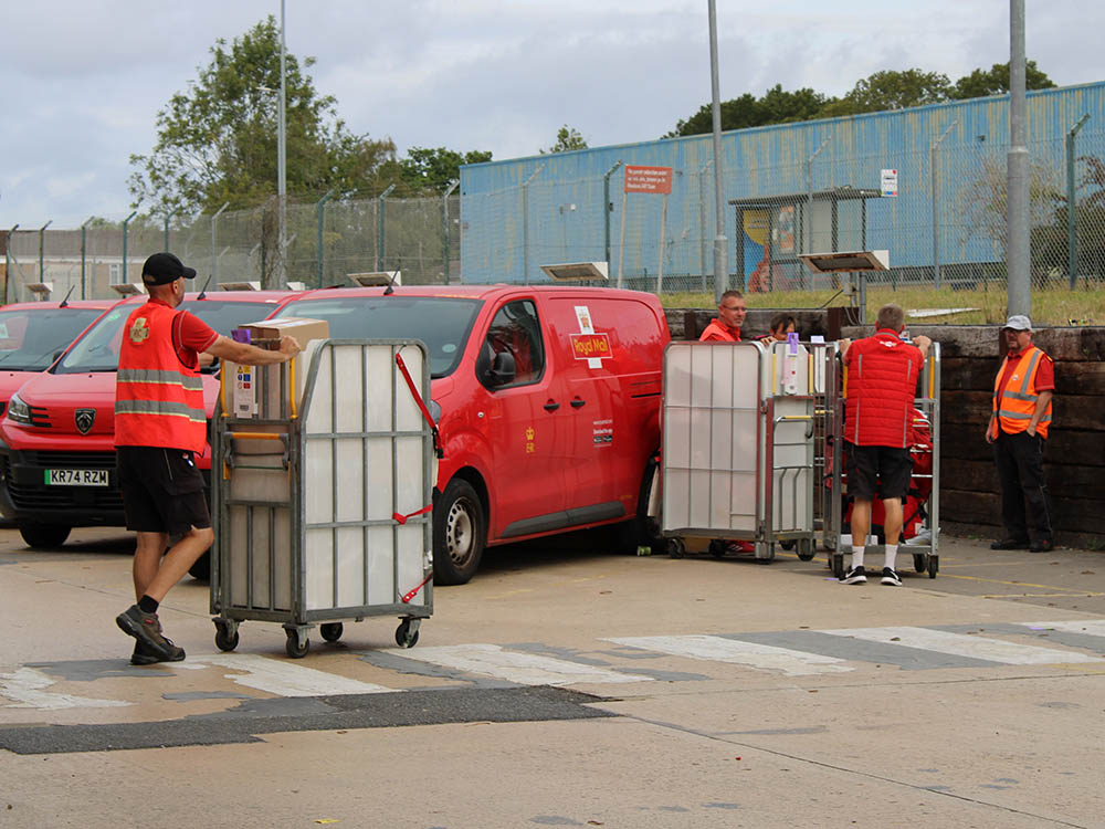 Uniformed drivers moving mail in trolleys.