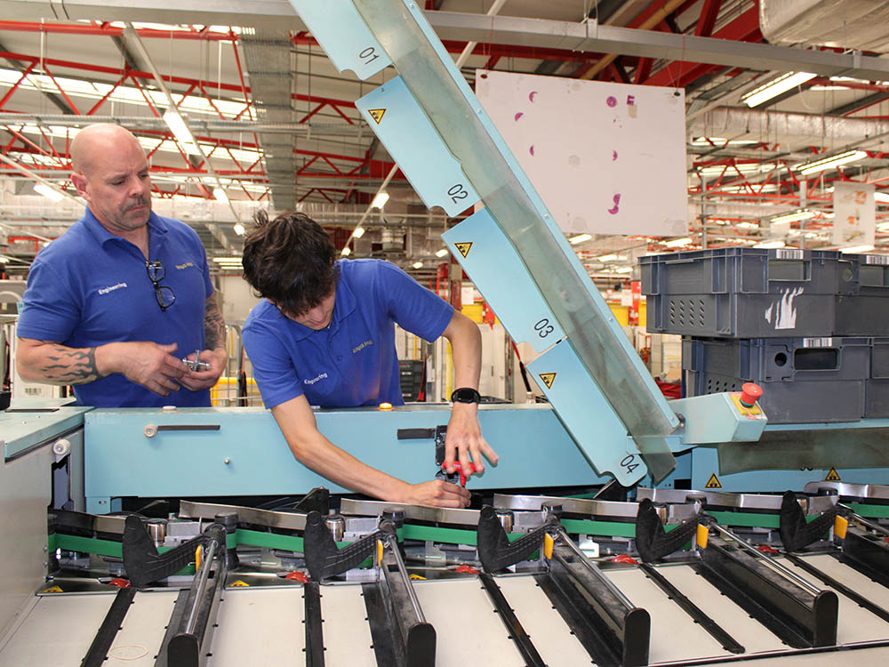 Engineers in blue uniform working at a machine.