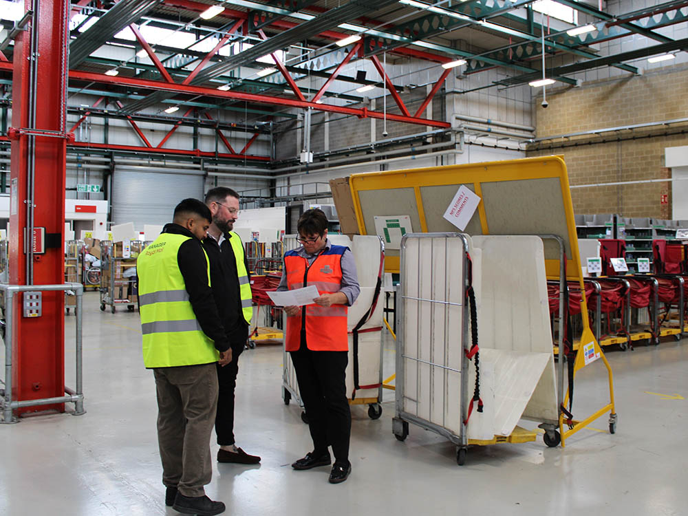 Three office workers standing in the mail centre.