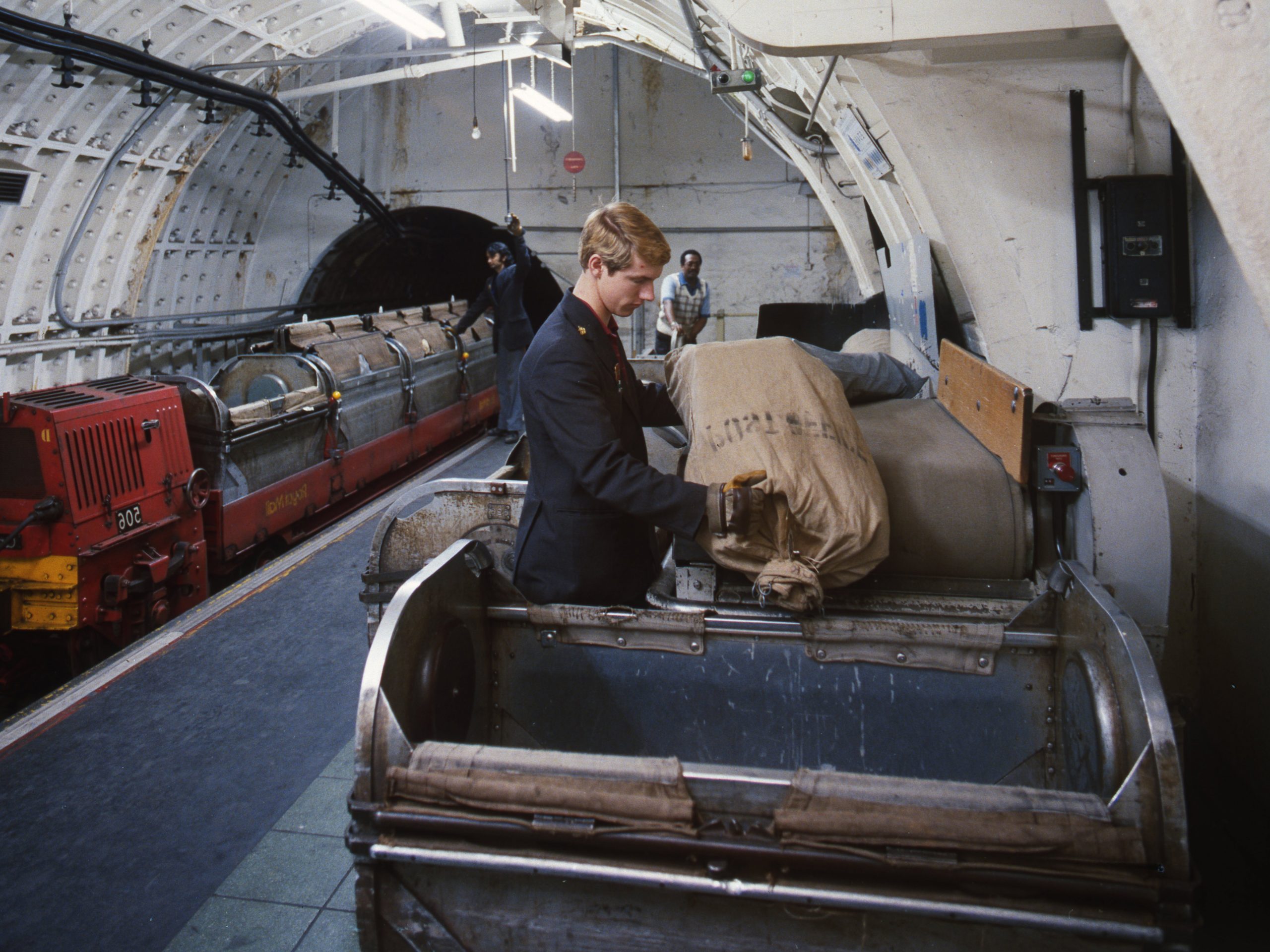 A man empties a sack of mail into a Mail Rail York container.