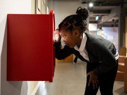 A child looking into a postbox in the exhibition space.