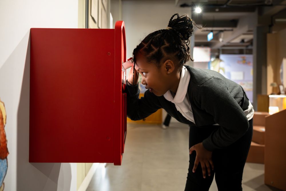 A child looking into a postbox in the exhibition space.
