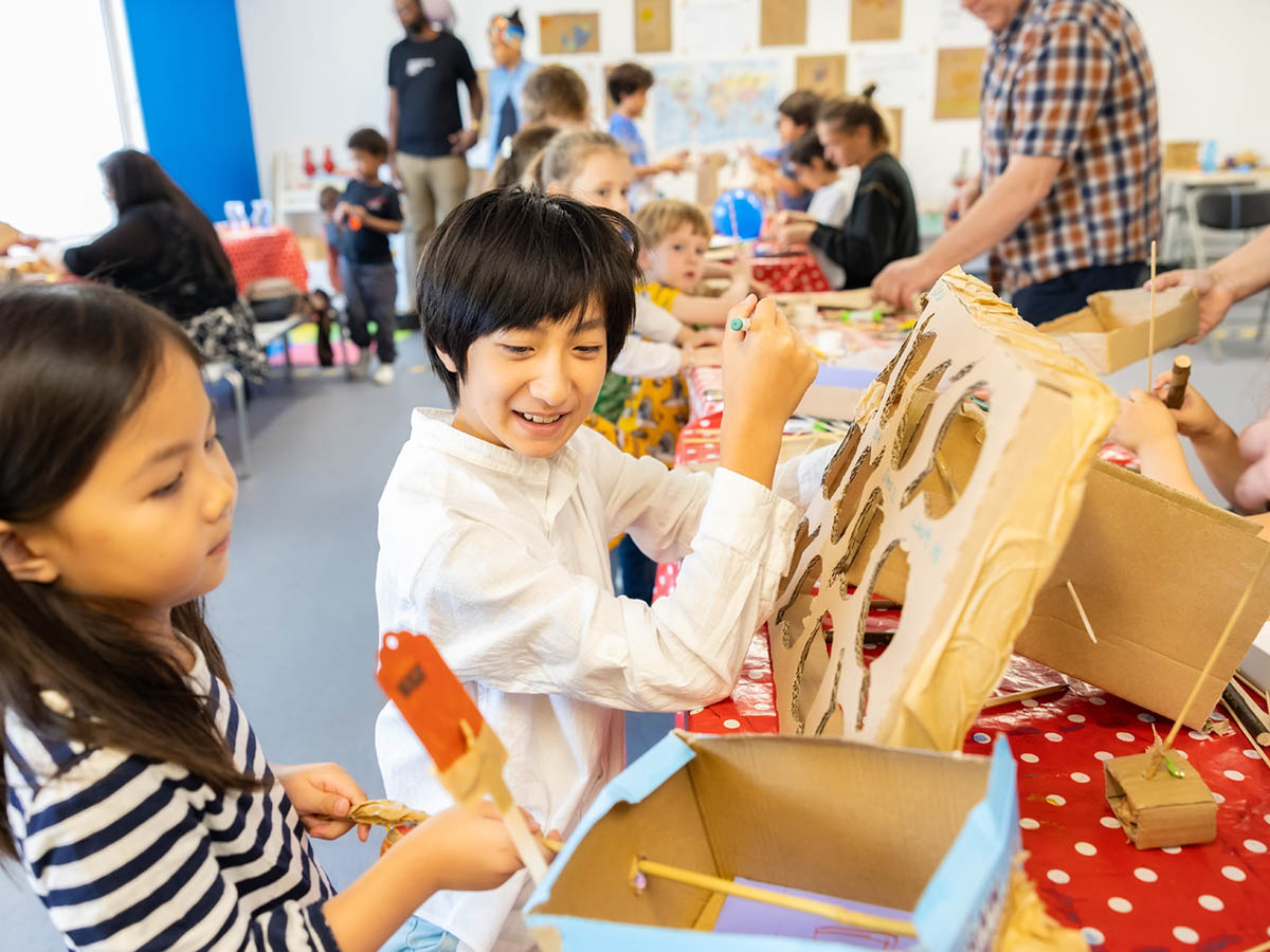 Children at an arts and crafts activity colouring with cardboard and paper.