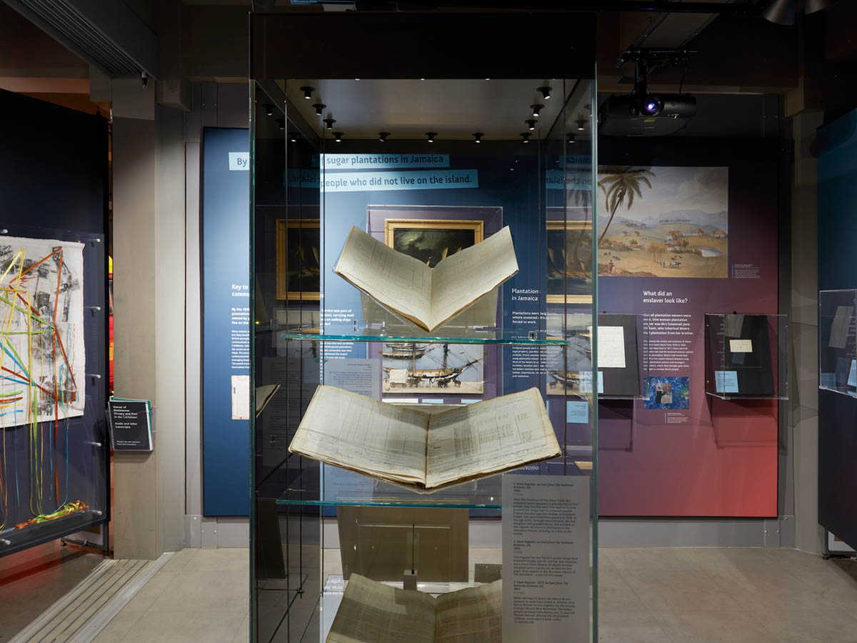 A glass exhibition case containing large books.