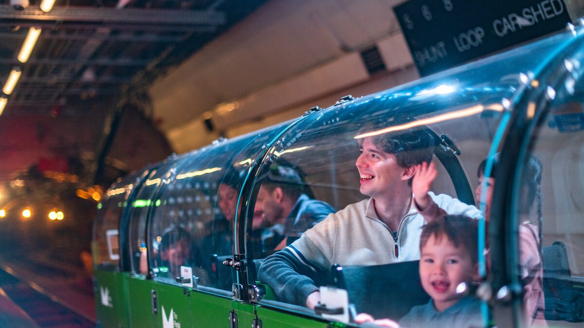 A family riding a miniature green train.