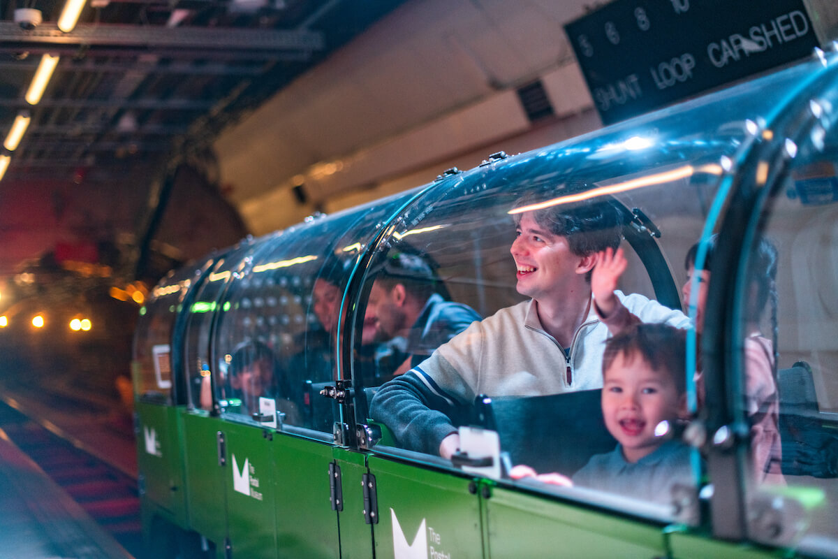 A family riding a miniature green train.