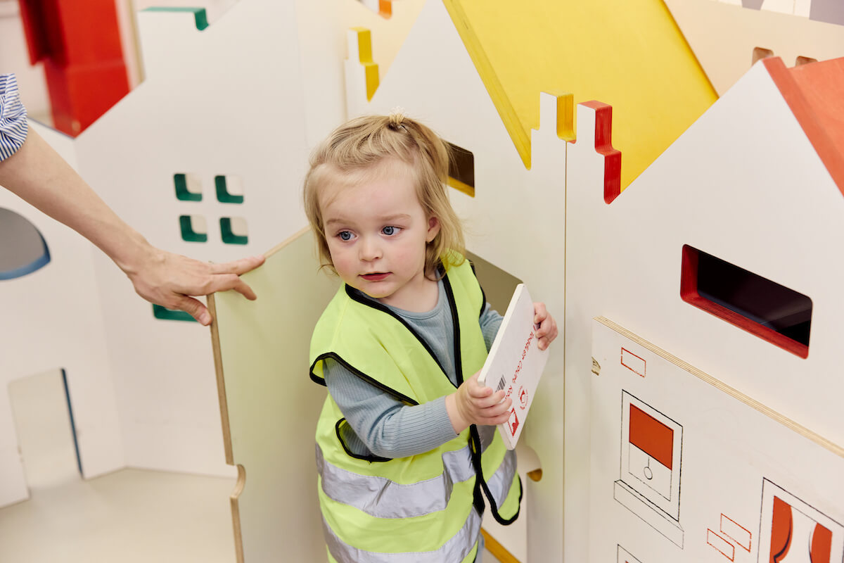 A child playing with a miniature door in a play space.