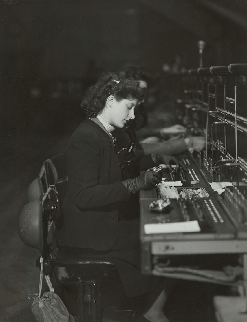 A woman working seated at a switchboard.