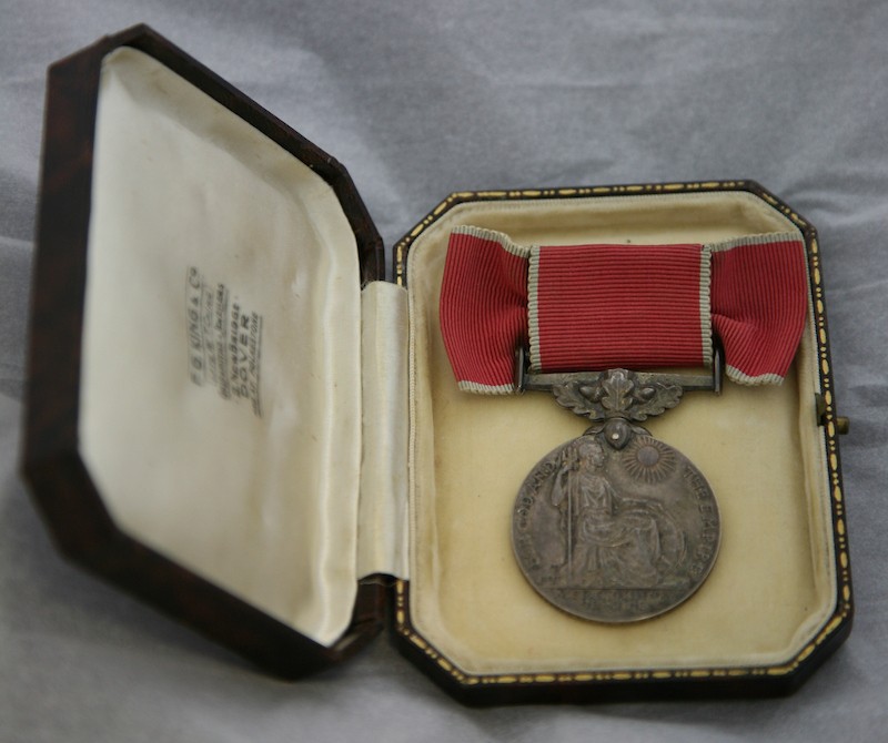 A medal in a small box with a red ribbon.
